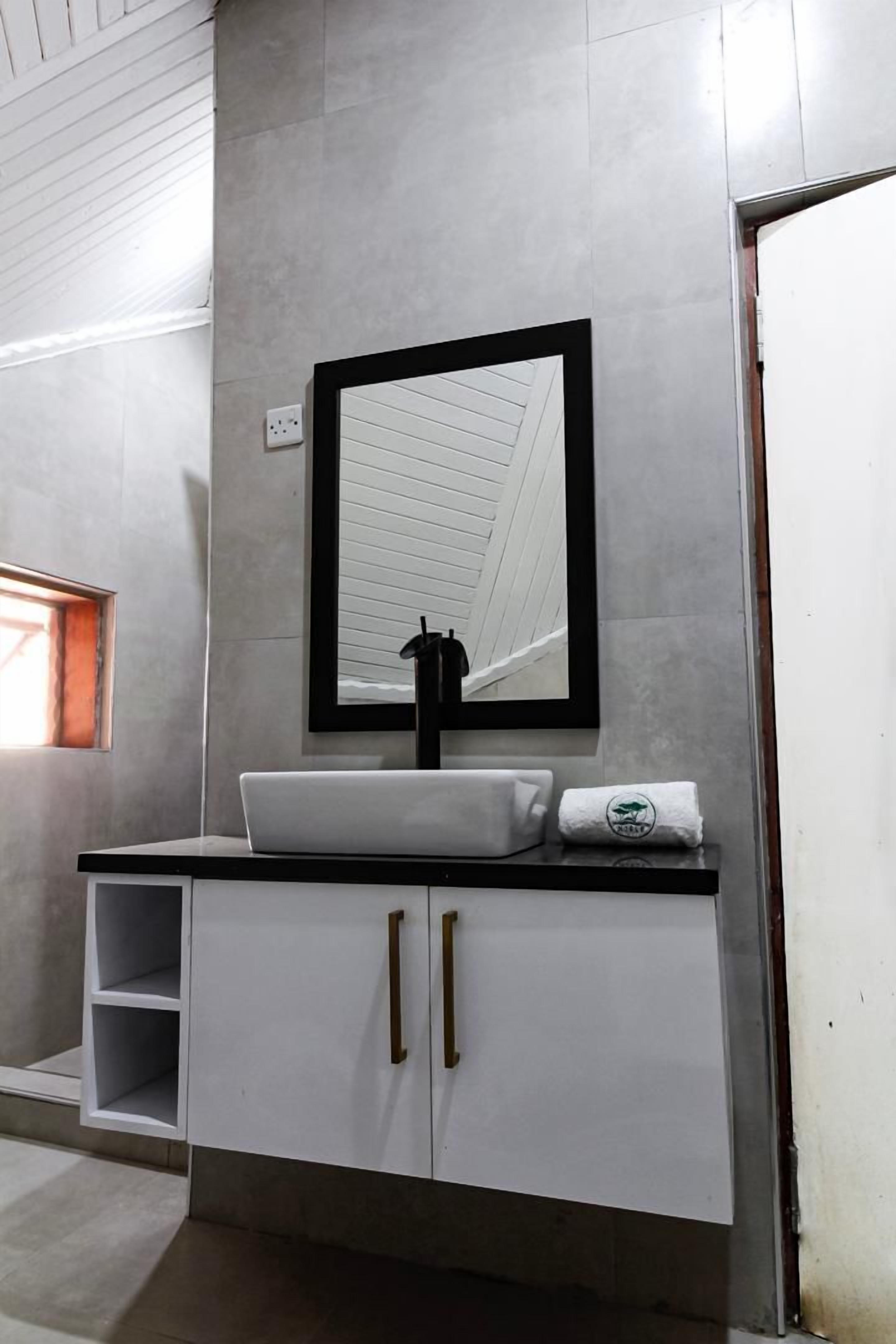 A bathroom with a white sink, black faucet, and a mirror with a black frame.