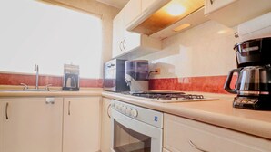 Cucina con piano cottura a gas, forno, macchina da caffè e una finestra vista.