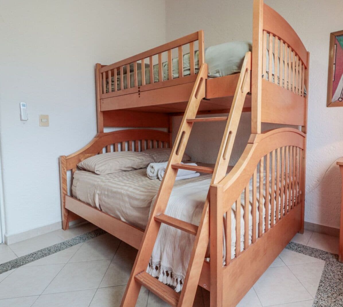 A bunk bed with a wooden ladder, a pillow, and a blanket.