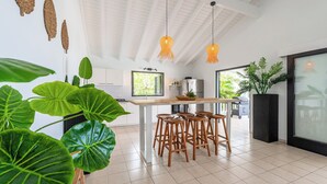 A modern kitchen with a central island, bar stools, and hanging lights.