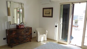 A bedroom with a bed, a dresser, a chair, a sliding glass door, and a framed picture on the wall. - Loft San Giovanni In Gallipoli (Gallipoli)