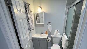 Een kleine badkamer met toilet, wastafel en douchehoek.