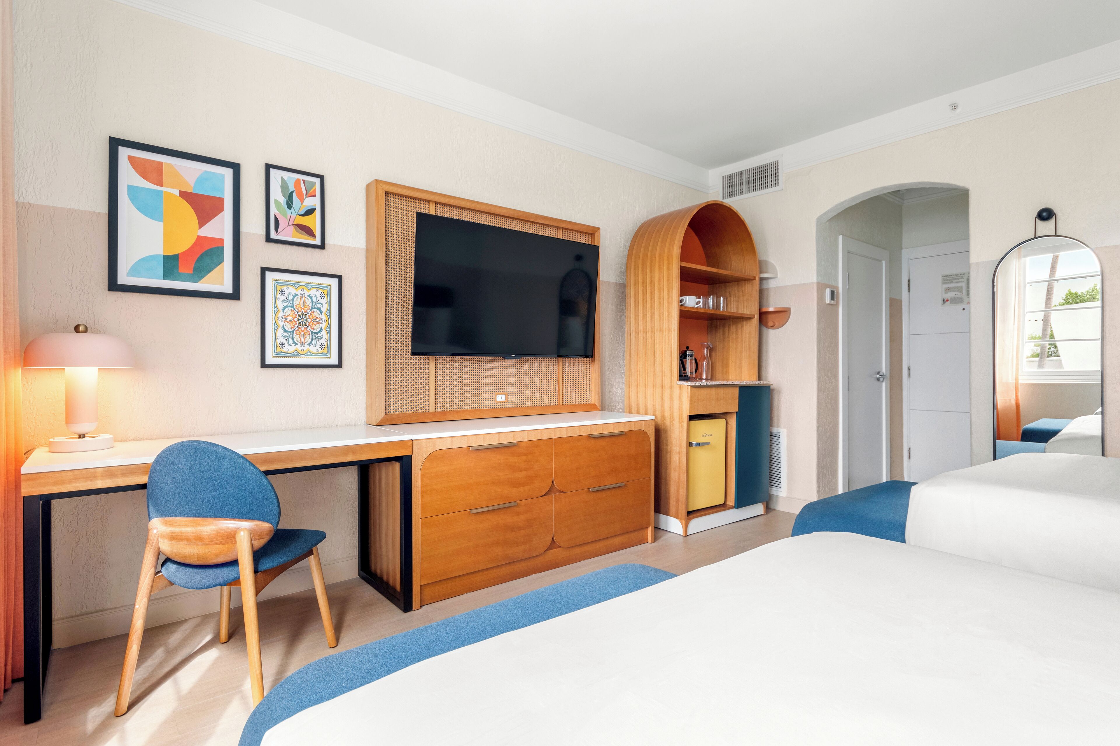 A hotel room with a wooden desk, a television, a bed, and a wardrobe.
