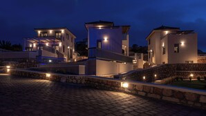Ein modernes Haus mit mehreren Ebenen, Steinmauern und Außenbeleuchtung.