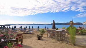 A beachside restaurant with outdoor seating, umbrellas, and a view of the sea. - Villa Située Dans un Domaine Prisé Avec Plage Privée + Transats ! (Grimaud)