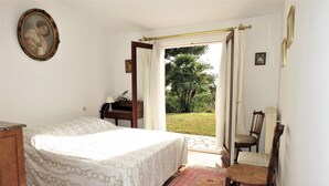 A bedroom with a bed, a chair, a desk, and a view of the outdoors. - Villa Située Dans un Domaine Prisé Avec Plage Privée + Transats ! (Grimaud)
