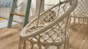 A macrame hanging chair in a room with a bunk bed and a ladder. - Crabby Coconut-Mid-Island 3BR Perfect for Families! Sleeps 8 (Fort Myers Beach)