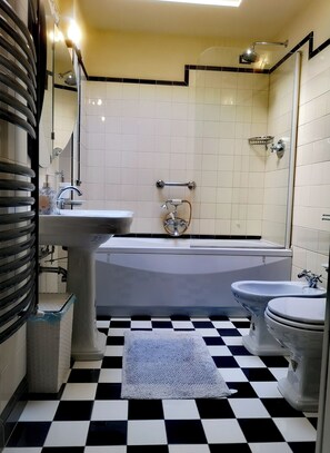 A bathroom with a checkered floor, a bathtub, a toilet, and a sink. - Cozy apartment with a garden terrace, near the central station and downtown (Milano)