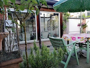 A patio area with a table and chairs, surrounded by potted plants and a glass door leading to a garden. - Cozy apartment with a garden terrace, near the central station and downtown (Milano)