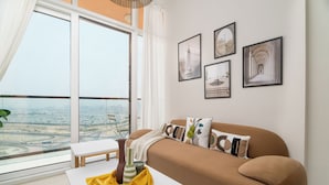 A modern living room with a sofa, a small table, and a view of a cityscape through large windows.