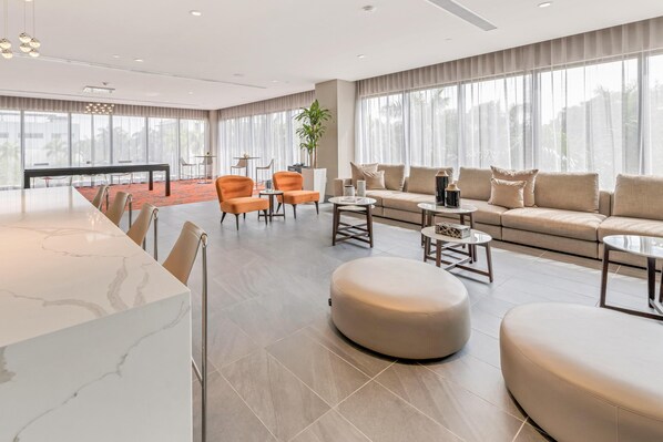 Un moderno vestíbulo de hotel con un mostrador de recepción de mármol, un conjunto de sofás y un comedor.