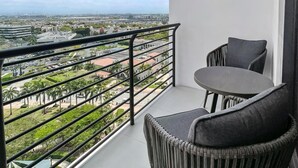 Ein Balkon mit Blick auf eine Stadtlandschaft, inklusive Tisch und zwei Stühlen.