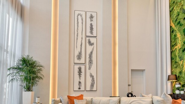 Ein modernes Wohnzimmer mit einem Ecksofa, einem Couchtisch und einer großen, strukturierten Wand in Grün.