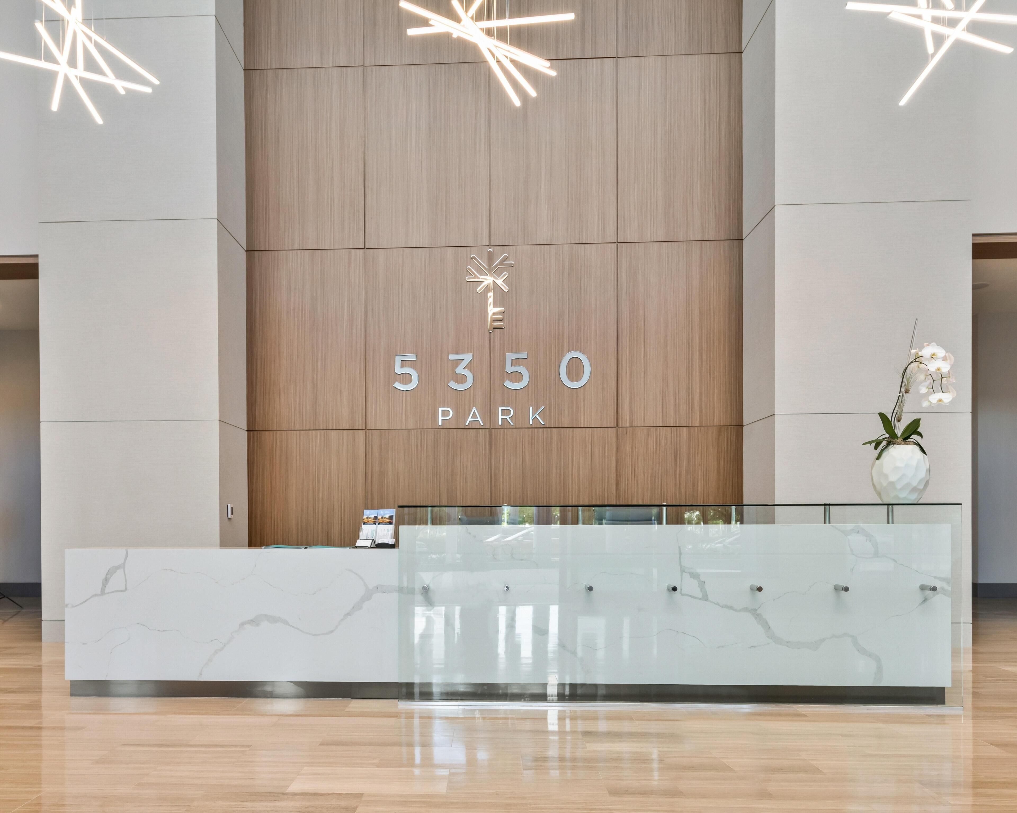 A reception desk with a marble top and a wooden panel wall behind it. The number '5350' and the word 'PARK' are visible on the wall.