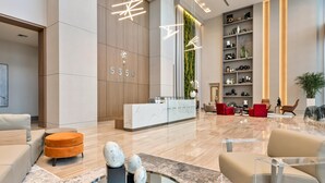 A modern hotel lobby with a reception desk, seating area, and a large bookshelf. - Relaxing Doral Retreat: 2BR Charm (Doral)