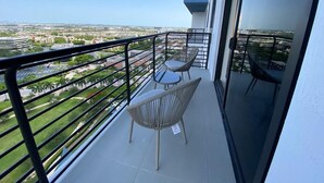 A balcony with two wicker chairs and a small table, overlooking a cityscape. - Relaxing Doral Retreat: 2BR Charm (Doral)