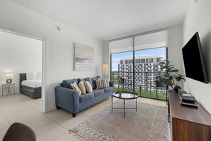 A modern living room with a sofa, coffee table, and a large window with a view of a building.
