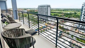 Un balcón con mobiliario exterior, vistas a un paisaje urbano y cielo despejado.
