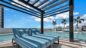 Zona junto a la piscina con una tumbona y piscina.
