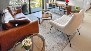 Un salon moderne avec un canapé, un fauteuil, une table basse et un téléviseur.