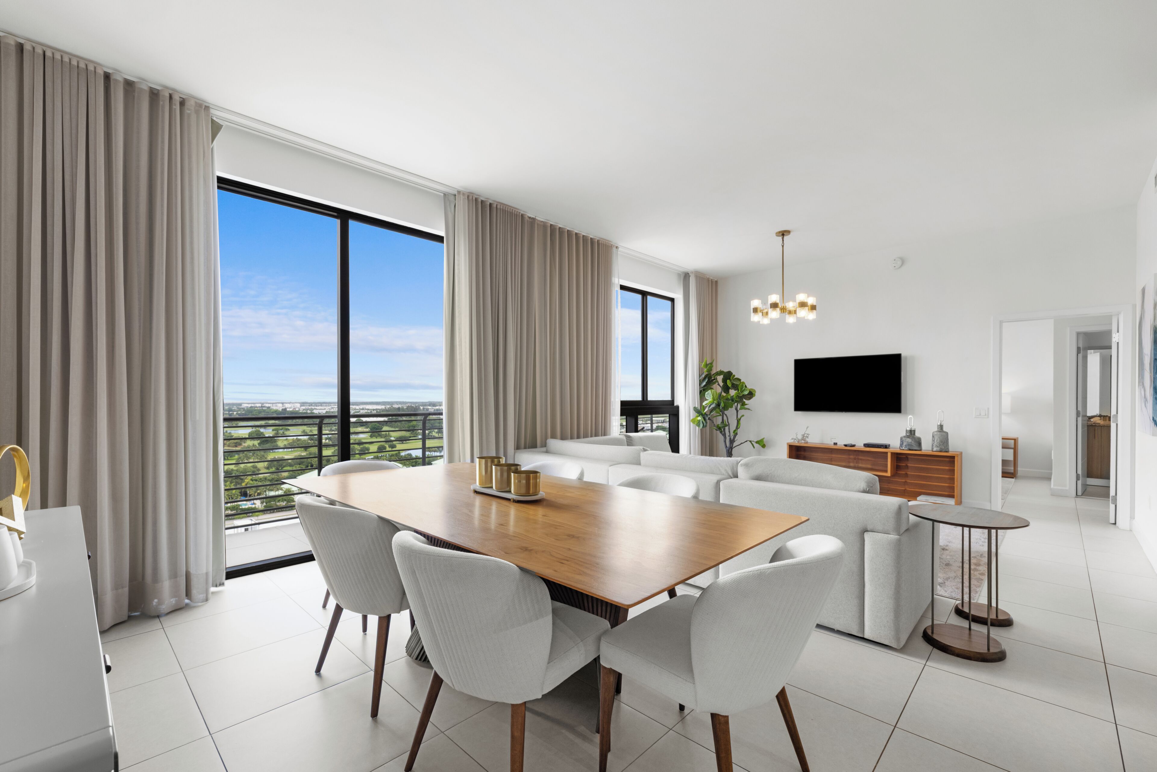 Una sala de estar moderna con comedor, ventanas amplias y un televisor de pantalla plana.