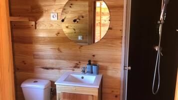 A wooden bathroom with a toilet, sink, and shower.