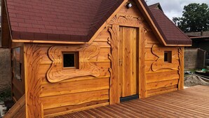 Une cabane en bois avec un toit en pente, une porte centrale et deux petites fenêtres.