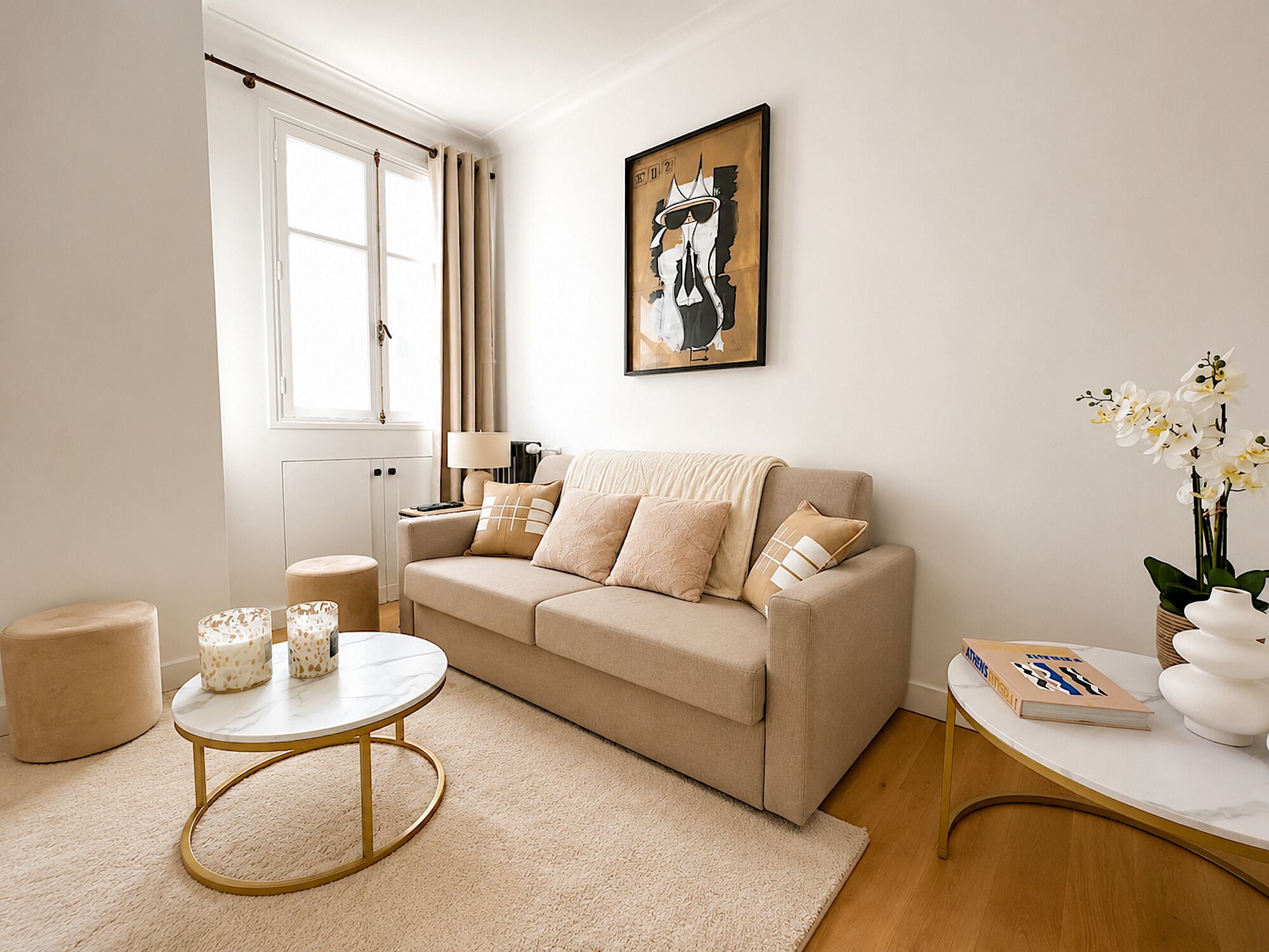 A living room with a beige sofa, a round coffee table, a lamp, and a framed artwork on the wall.