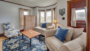 A cozy living room with a wooden coffee table, beige sofas, a floral armchair, and a patterned rug. - Spacious, family friendly 5-bedroom home in Pittsburg village with trail access. (Pittsburg)