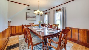 A dining room with a wooden table set for six, surrounded by six chairs. - Spacious, family friendly 5-bedroom home in Pittsburg village with trail access. (Pittsburg)