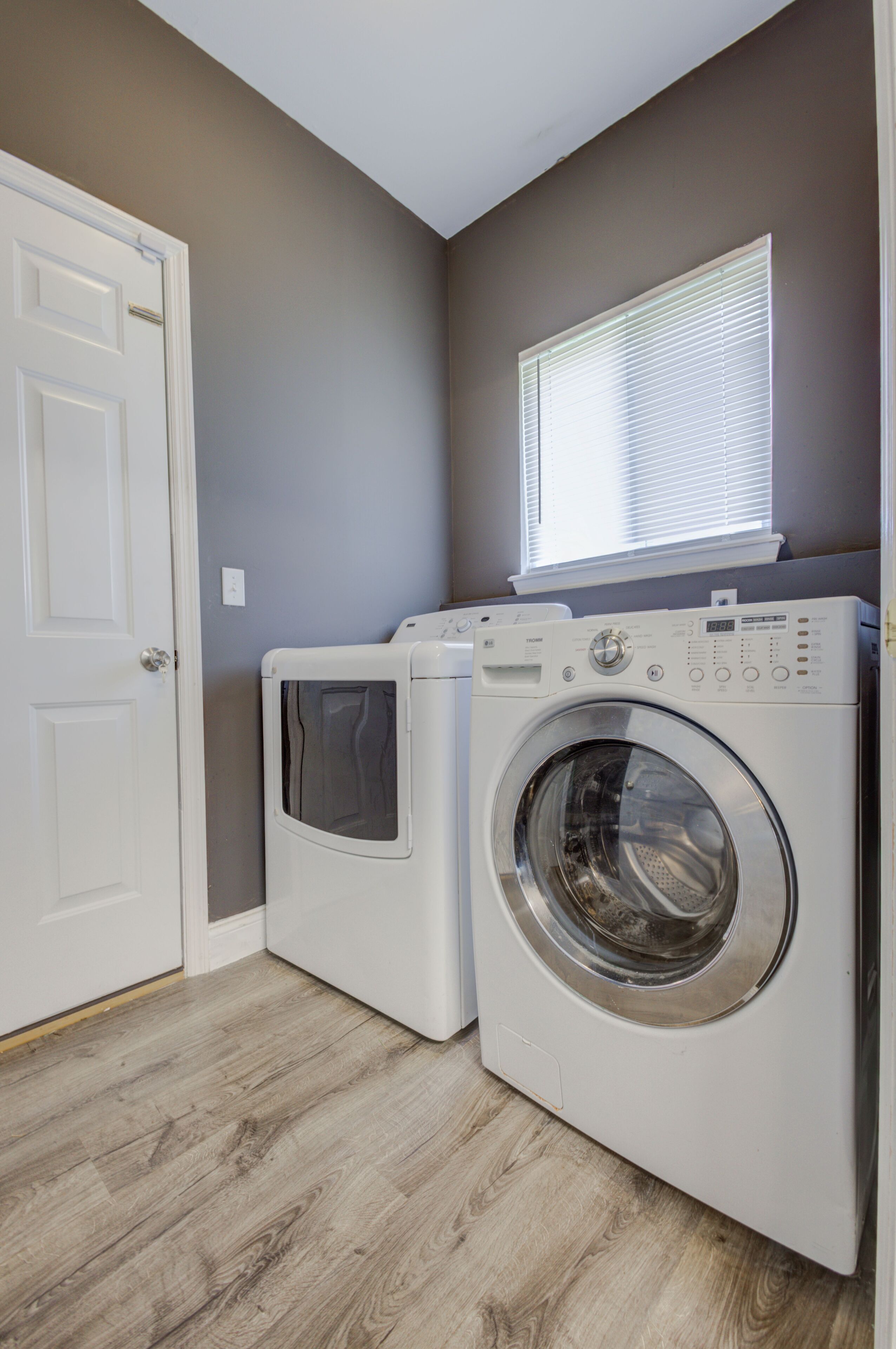 A laundry room with two white front-loading washing machines and a window above them.