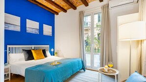 A bedroom with a bed, a small table with a drink, a chair, and a window with a view of buildings. - BARCELONETA BEACH STUDIO 11 (Barcelona)