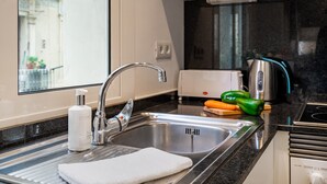 A modern kitchen with a stainless steel sink, a built-in oven, and a window overlooking a balcony. - BARCELONETA BEACH STUDIO 11 (Barcelona)