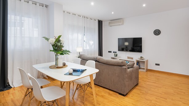 A modern living room with a white table, grey sofa, and a flat-screen TV. - VILLA DE GRACIA APARTMENT (Barcelona)