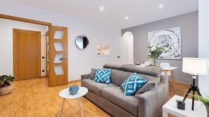 A modern living room with a grey sofa, a round mirror, and a painting on the wall. - VILLA DE GRACIA APARTMENT (Barcelona)
