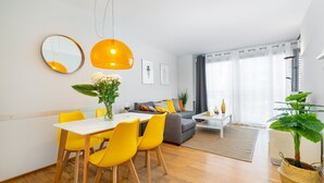 Ein modernes Wohnzimmer mit Essbereich, ausgestattet mit einer Couch, einem Couchtisch und einem Esstisch mit gelben Stühlen.