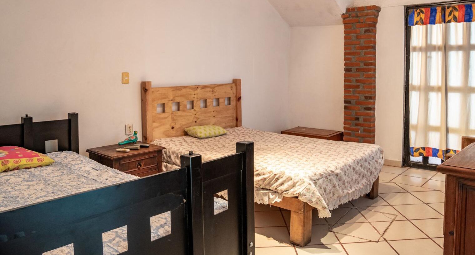 Un dormitorio con dos camas, una chimenea de ladrillo y un ventanal con cortinas.