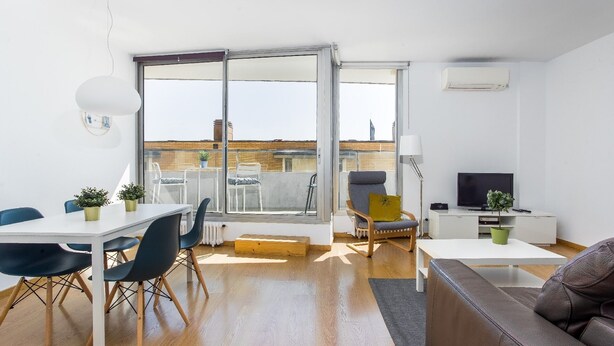 A modern living room with a dining area, a sofa, a TV, and a balcony with a view of the city. - BEACH APARTMENT VILLA OLIMPICA (Barcelona)