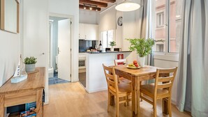 Eine moderne Küche mit weißen Schränken, einem Holztisch und einer Pendelleuchte.