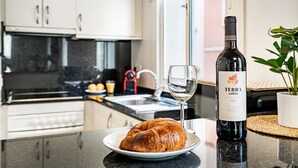 Eine Küche mit einem Croissant auf einem Teller, einer Flasche Terra Calida Wein und einem Weinglas.