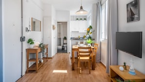 A modern kitchen with white cabinets, a wooden dining table, and a pendant light. - BARCELONETA BEACH STUDIO 42 (Barcelona)