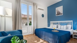 A bedroom with a bed, a nightstand, a lamp, a window with curtains, and a view of the outside. - BARCELONETA BEACH STUDIO 42 (Barcelona)