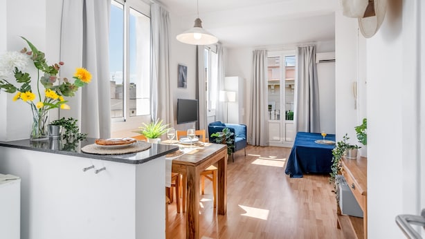 A modern kitchen with a dining area, large windows, and a view of the city. - BARCELONETA BEACH STUDIO 42 (Barcelona)