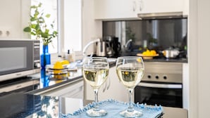 A modern kitchen with two wine glasses on a reflective surface, a sink, and a stove.