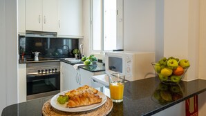 A modern kitchen with white cabinets, a stainless steel oven, a microwave, and a glass of orange juice on the counter. - BARCELONETA BEACH STUDIO 22 (Barcelona)
