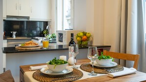 A breakfast setup with a table, chairs, a bowl of greens, a croissant, a glass of orange juice, and a bottle of wine. - BARCELONETA BEACH STUDIO 22 (Barcelona)