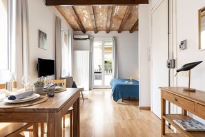 Una habitación con una mesa de madera, un televisor y una cama con colcha azul.