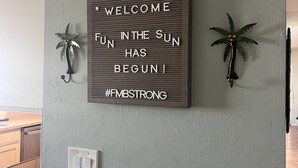 Een wandbord met motiverende tekst en decoratieve palmplanten.