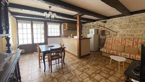 Une cuisine rustique avec un mur en pierre, une table à manger en bois et un canapé recouvert d’un tissu à motifs floraux.