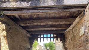 Un arc en pierre qui mène à un chemin pavé, avec un banc.